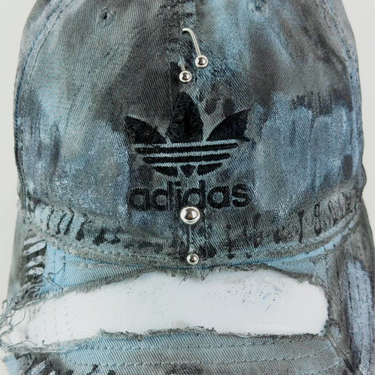 Close-up of ASTROBOI* x Adidas 'Margiela' showing black embroidered Adidas logo and blue and black painterly distressing.