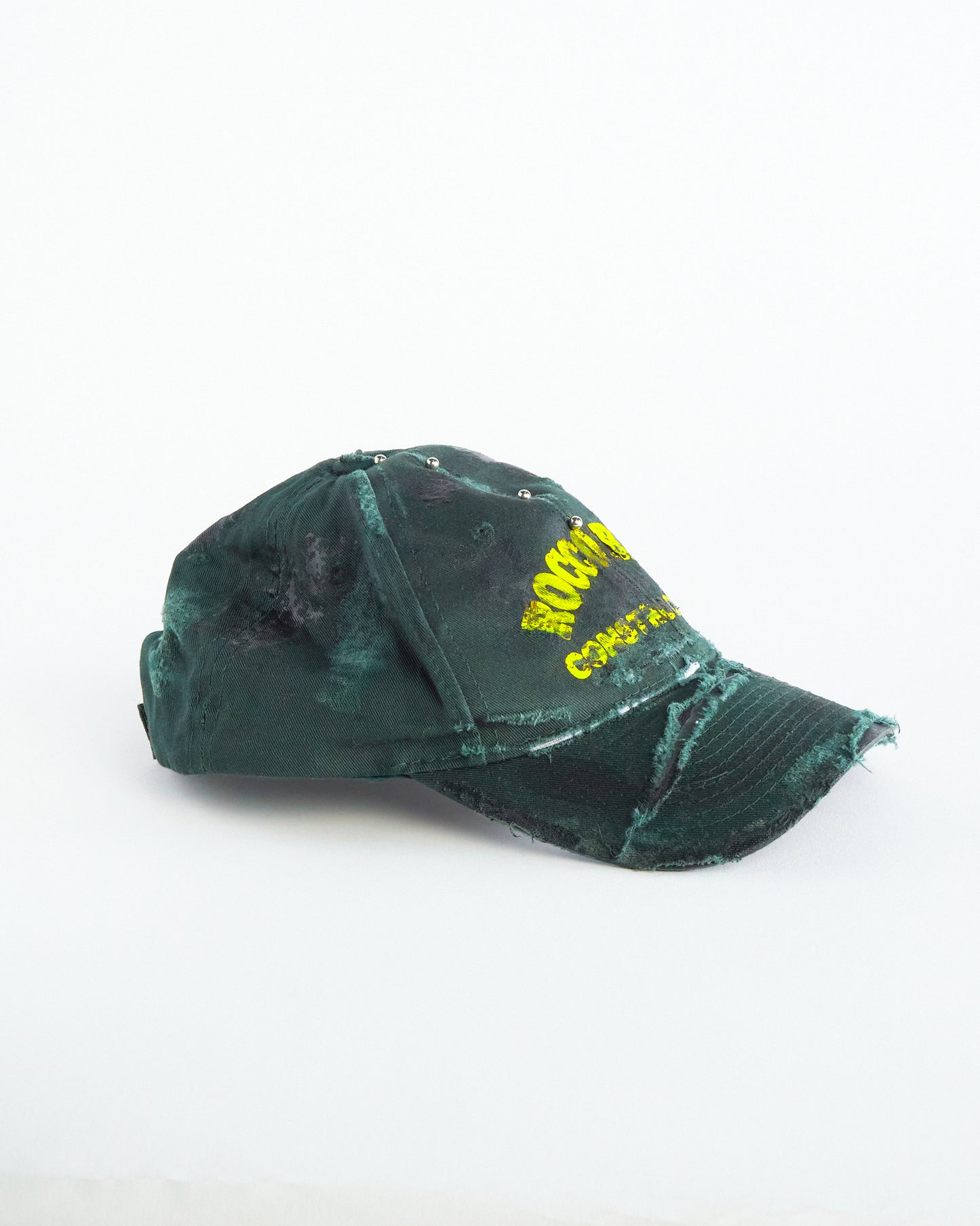 Right of ASTROBOI* Rocco Bros green construction hat with black grease distressing, stainless steel piercings, adjustable strap, handmade in NYC.