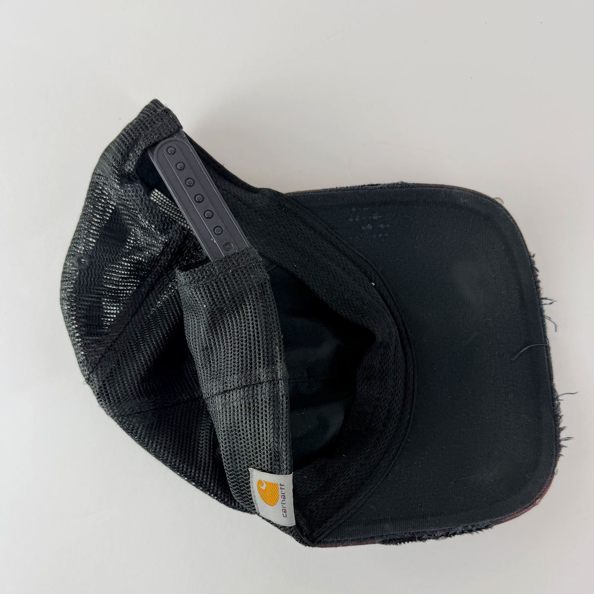 Rear view showing black mesh panel, original Carhartt logo patch, and adjustable fit.
