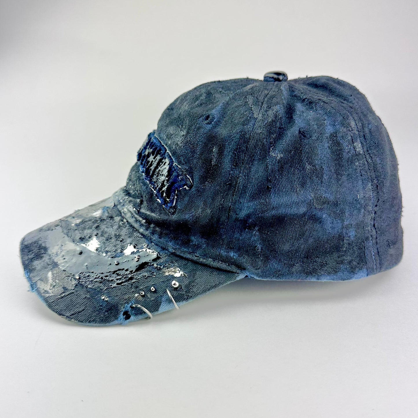Left side of ASTROBOI* Zypher NYC navy distressed hat with metallic silver paint, black resin logo and brim, adjustable back streetwear cap.