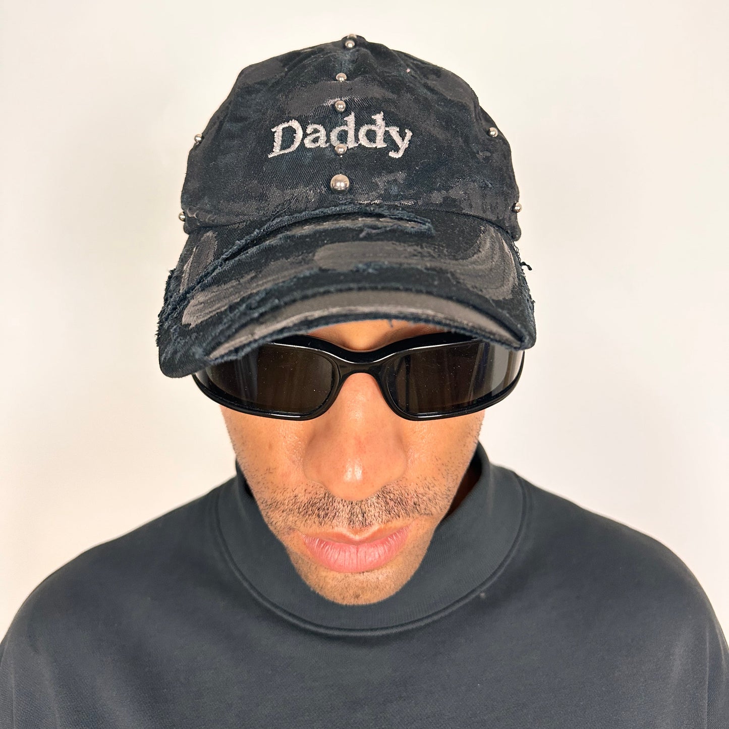 Overview of Black distressed ASTROBOI* ‘Daddy’ hat with custom paint detailing and stainless steel piercings, handcrafted in NYC.