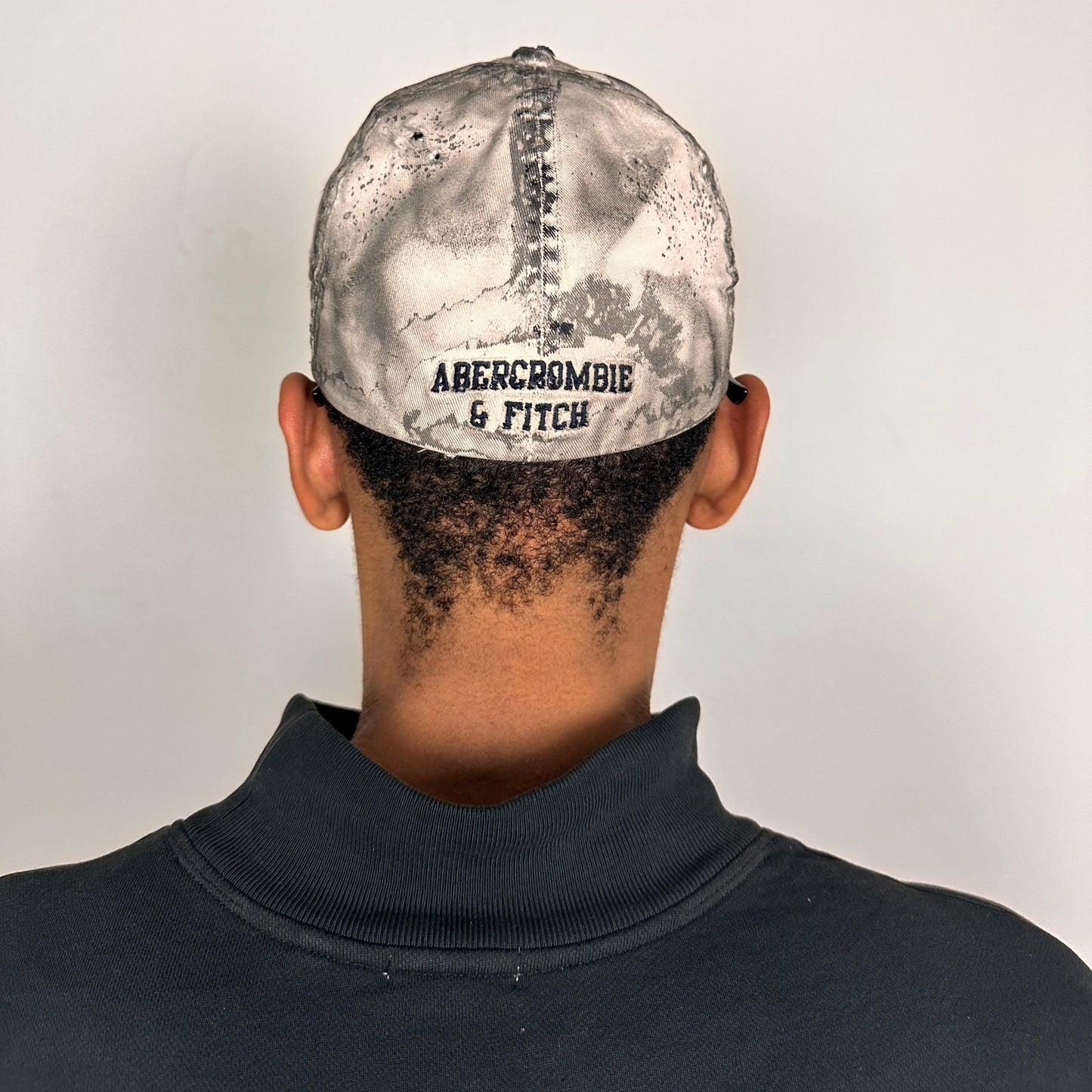 Back of Off-white and black faded ASTROBOI* x Abercrombie hat with custom paint treatment and stainless steel piercing, handmade in NYC.
