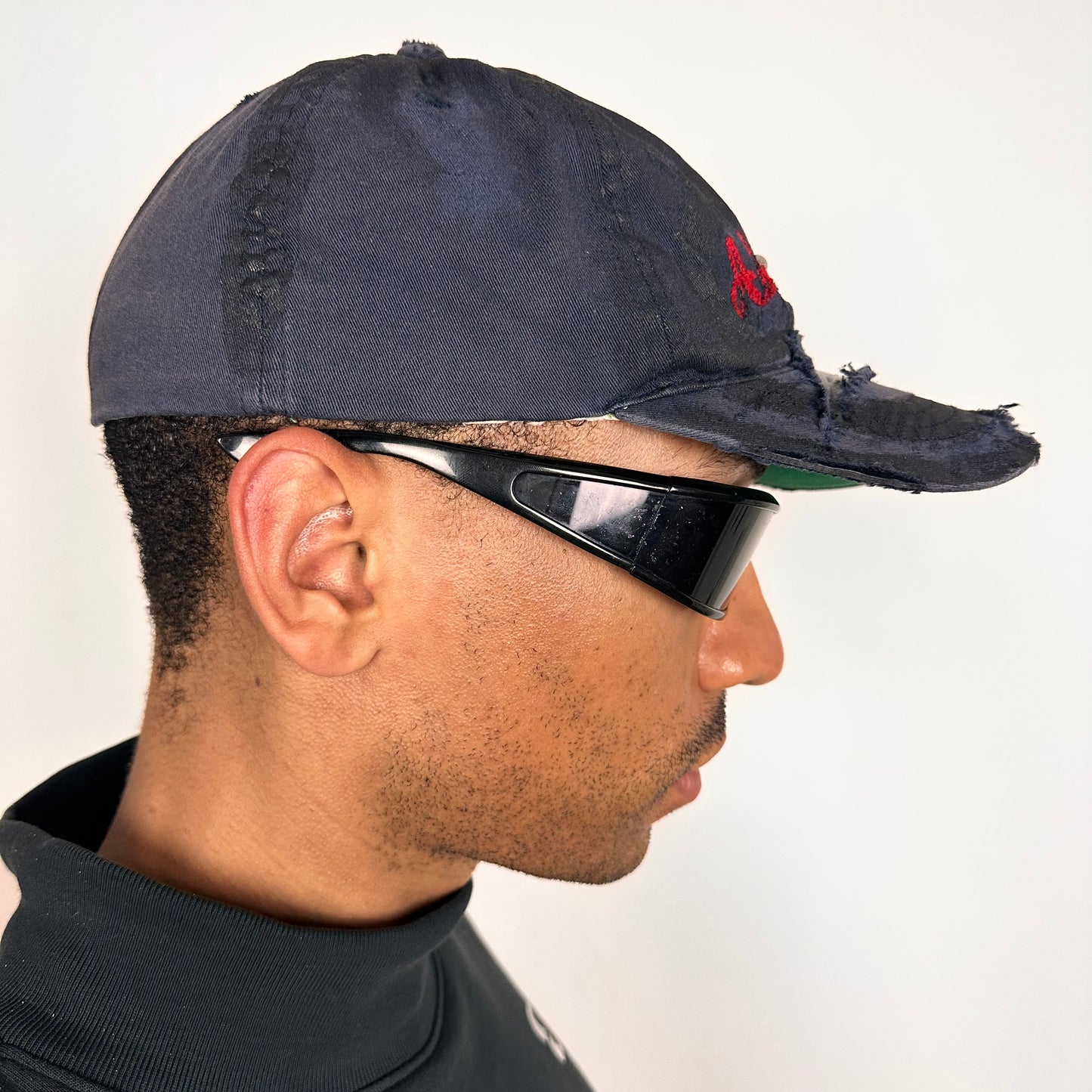 Right side of Navy ASTROBOI* x Abercrombie hat with distressed paint, stainless steel piercings, and logo embroidery on front and back, customized in NYC.