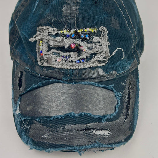 Close up product shot of ASTROBOI* New York Aquarium navy distressed baseball hat with resin-sealed rhinestone logo, black waxed paint details, adjustable strap, custom NYC piece