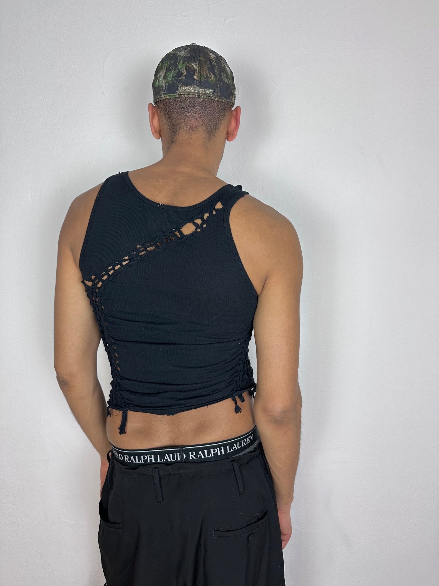 ASTROBOI* 'Morningstar' black braided twist tank top, rear view showing braid, knot, and cut-out construction, worn by male model.