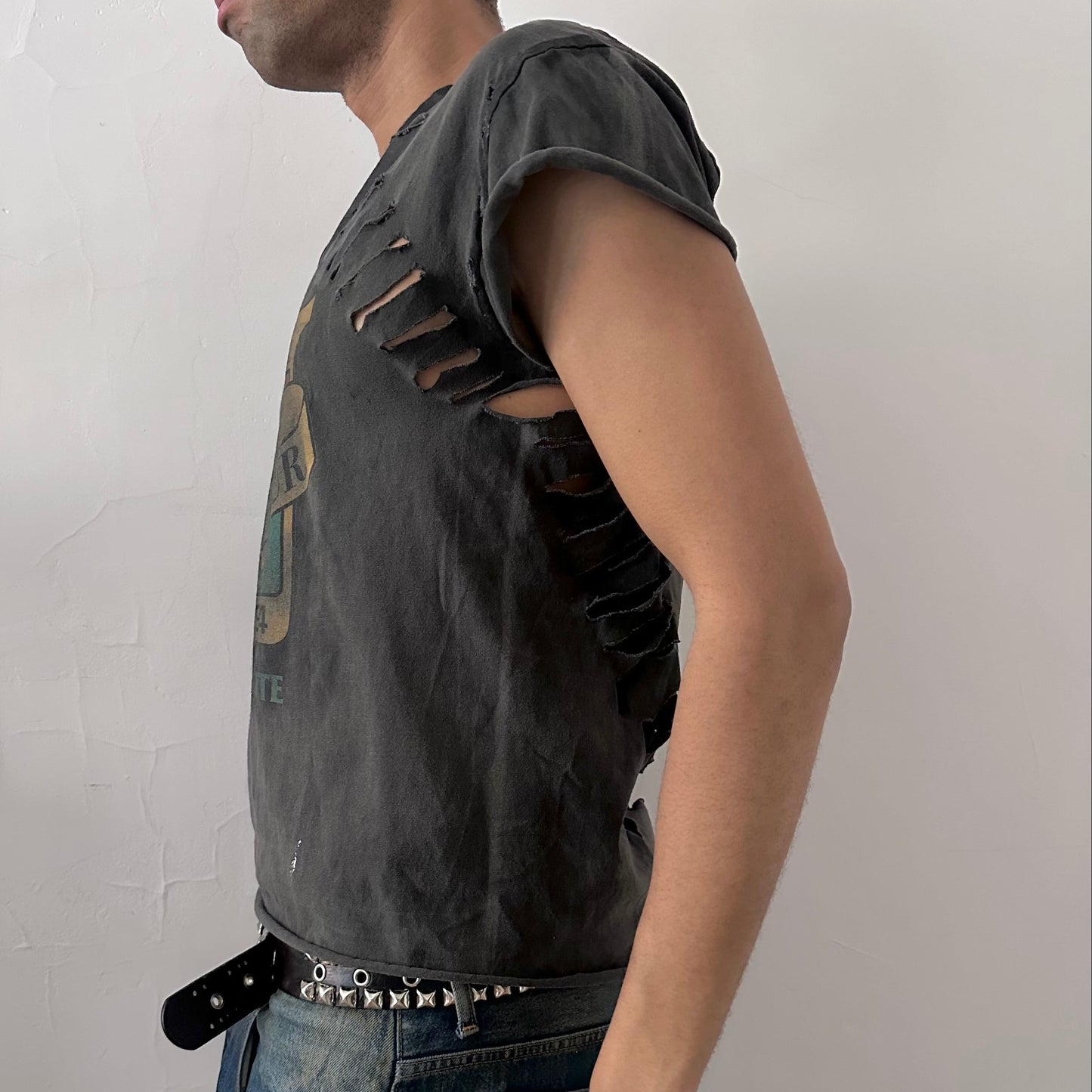 Left side detail of ASTROBOI* NCAA Basketball tank showing subtle holes throughout body and raw edge detailing on black muscle tank.