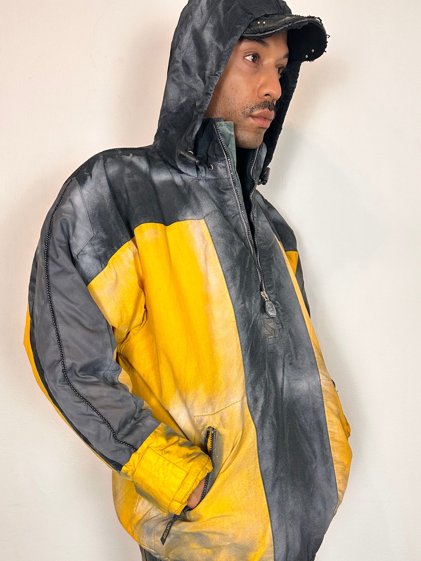 Hood detail of ASTROBOI* x Starter yellow and black airbrushed puffer jacket with grey sleeves, reflective taping, and adjustable toggles, men’s XL.
