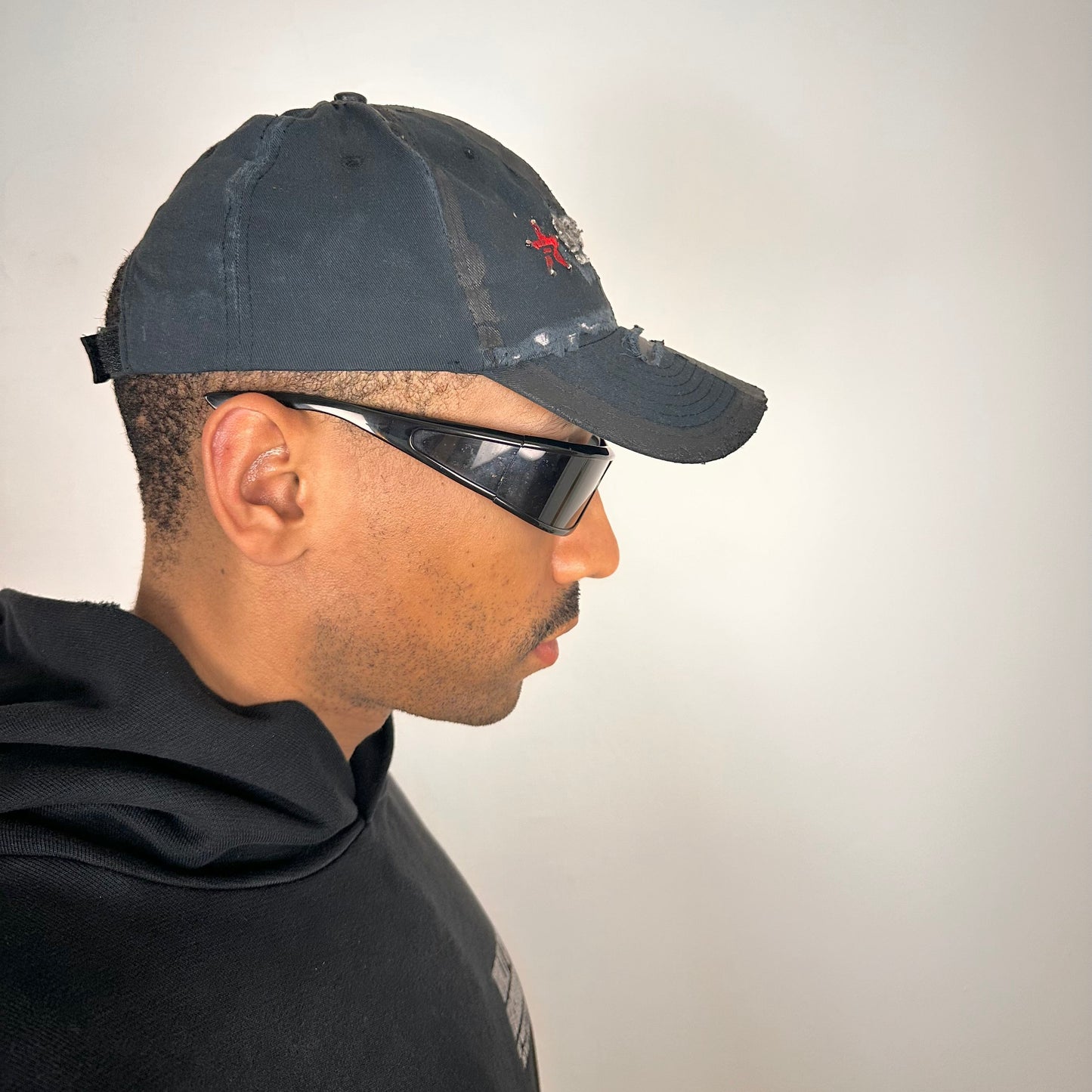 Right side of ASTROBOI* RBP navy and black distressed utility hat with deconstructed visor, rhinestone logo sealed in resin, adjustable strap, custom NYC piece