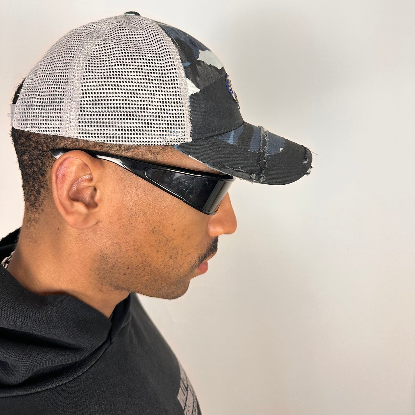 Right side of ASTROBOI* Costa blue and white camo rhinestone trucker hat with black waxed tattoo print, mesh back panels, adjustable strap, custom NYC piece