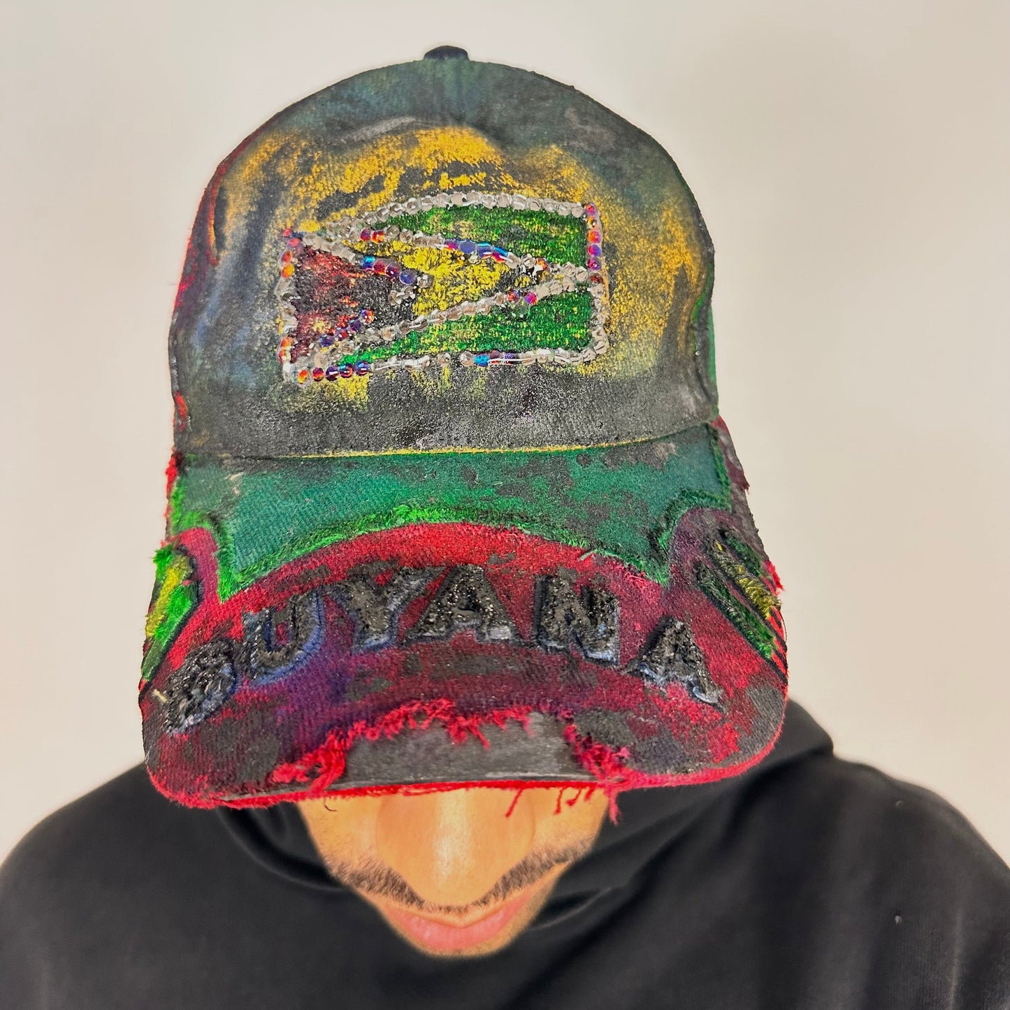 Cover image of ASTROBOI* Guyana yellow red green distressed baseball hat with resin-sealed rhinestone logo patch and adjustable strap, hand-customized in NYC