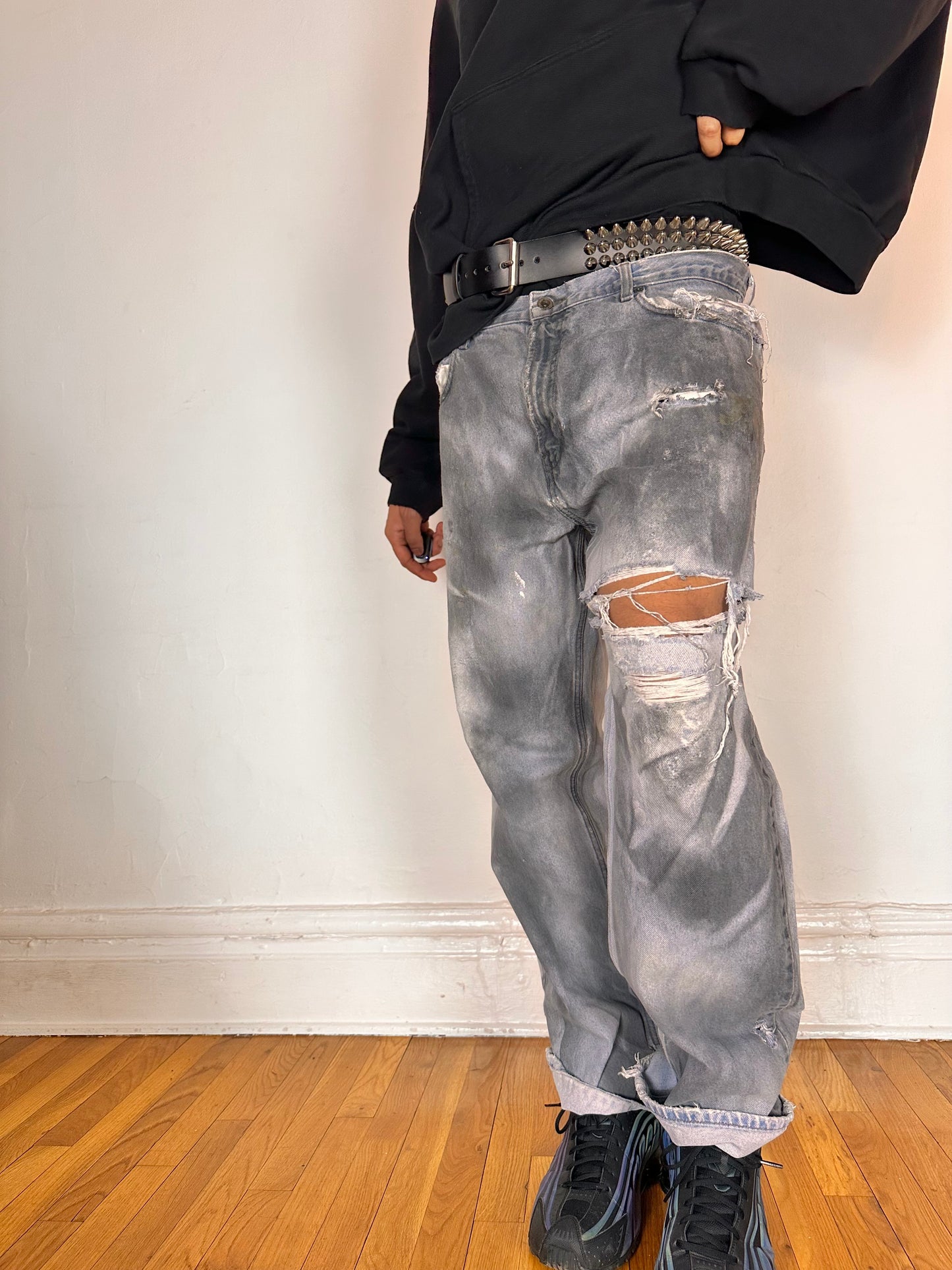 Posed photo of ASTROBOI* light rinse blue tar jeans with baggy fit, distressed cotton denim, and black and clay paint detailing, size 36x32