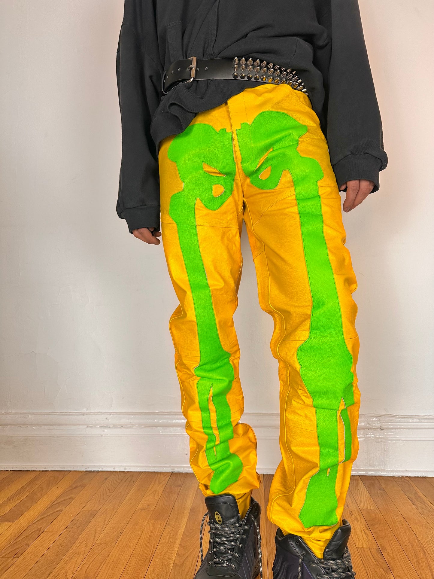 Styled image of Seeking green and yellow skeleton leather biker pants featuring a straight leg fit, bold skeleton detailing, and branded back patch. Size 36x36.