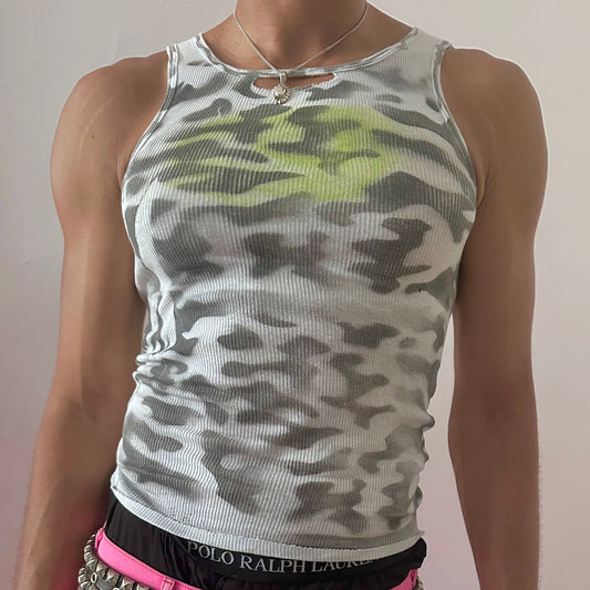 Close-up of ASTROBOI* x Hanes 'Bliss' showing black abstract camouflage print detail and lime green orb at center chest on white fabric.