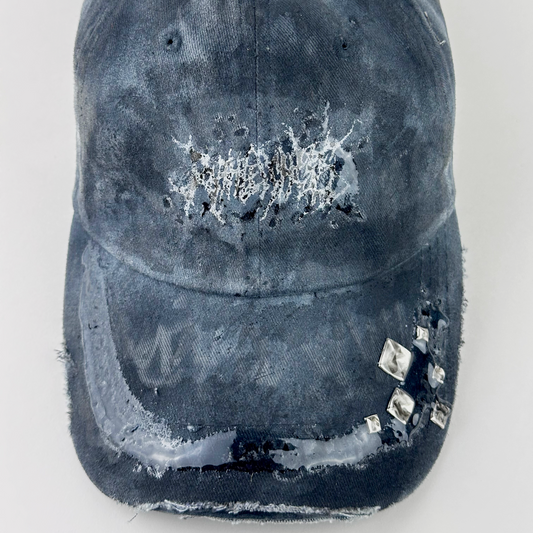 Close-up of ASTROBOI* 'Slick' showing white indie barbed wire logo and silver stud detail on visor sealed under 3D resin coating on black and gray fabric.