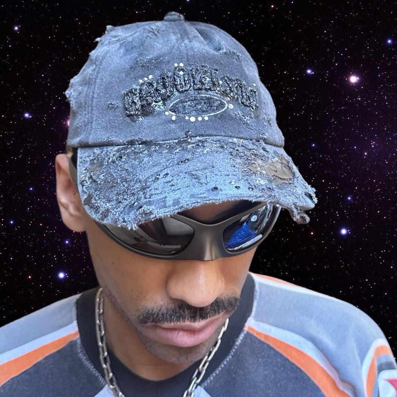 Styled image of ASTROBOI* 'Alastair' black distressed resin hat with clear resin-encased Brooklyn logo at center front, silver rhinestone embellishments, and custom black resin detailing, handcrafted in NYC.