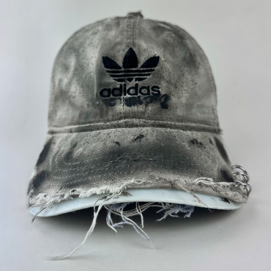 ASTROBOI* x Adidas 'H Chic' tan distressed grunge hat with black paint detailing, distressing, and Adidas logo at front, stainless steel piercings, front view.