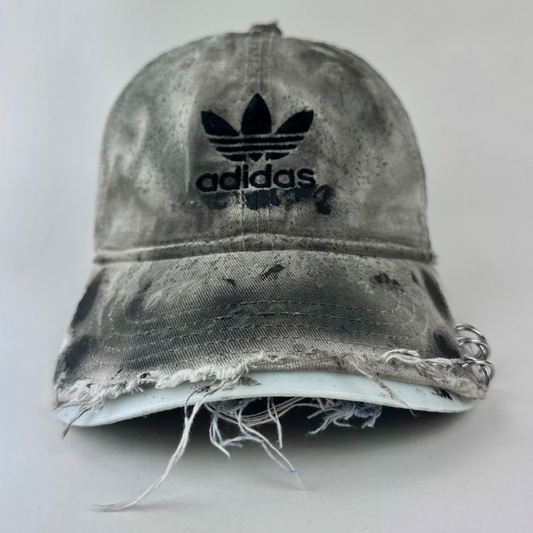 ASTROBOI* x Adidas 'H Chic' tan distressed grunge hat with black paint detailing, distressing, and Adidas logo at front, stainless steel piercings, front view.