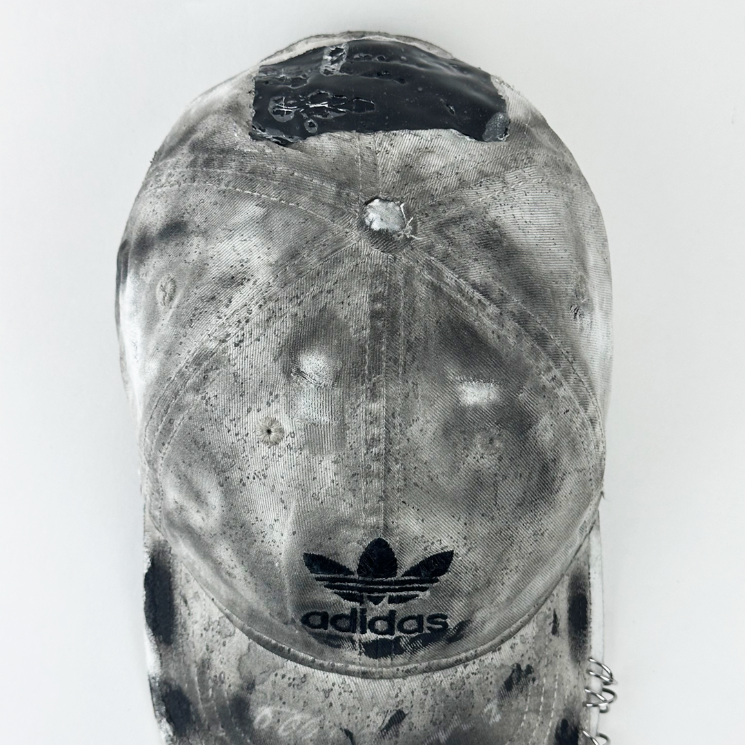 Top view of ASTROBOI* x Adidas 'H Chic' showing Adidas logo, black paint detailing, distressed finish, and stainless steel piercing detail on tan base.