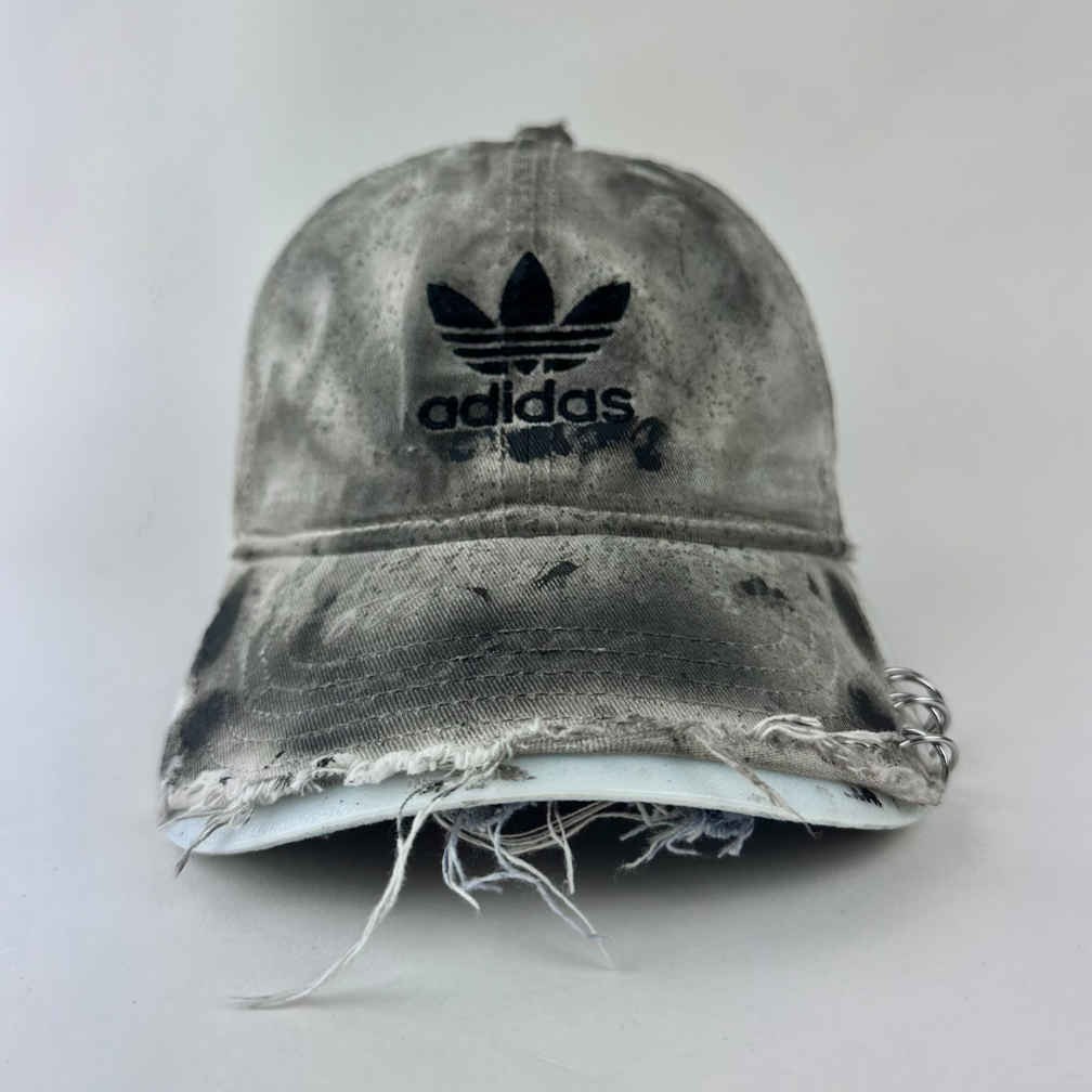 ASTROBOI* x Adidas 'H Chic' tan distressed grunge hat with black paint detailing, distressing, and Adidas logo at front, stainless steel piercings, front view.