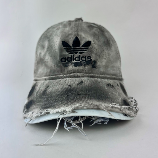ASTROBOI* x Adidas 'H Chic' tan distressed grunge hat with black paint detailing, distressing, and Adidas logo at front, stainless steel piercings, front view.