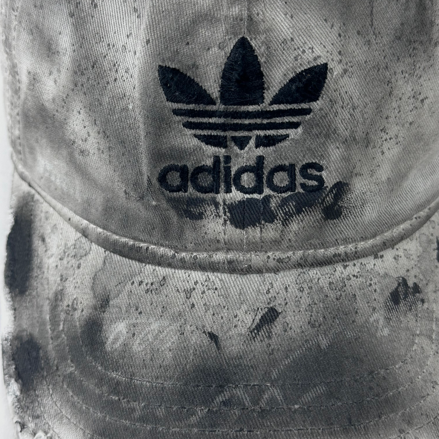 Close-up of ASTROBOI* x Adidas 'H Chic' showing Adidas logo, black paint detailing, distressed finish, and stainless steel piercing detail on tan base.