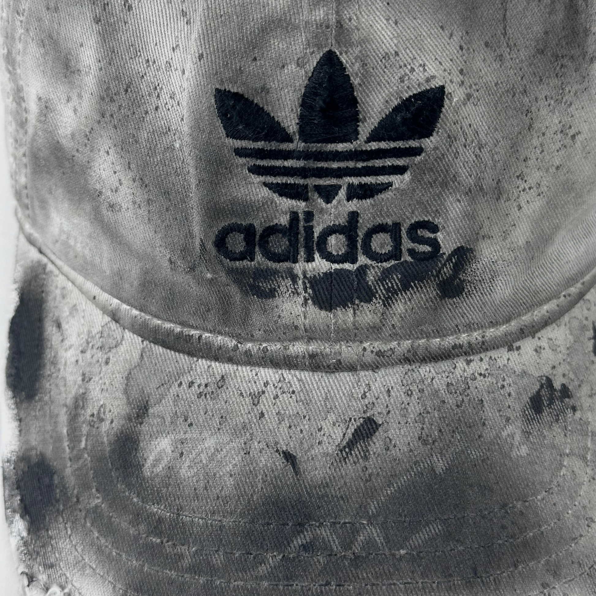 Close-up of ASTROBOI* x Adidas 'H Chic' showing Adidas logo, black paint detailing, distressed finish, and stainless steel piercing detail on tan base.