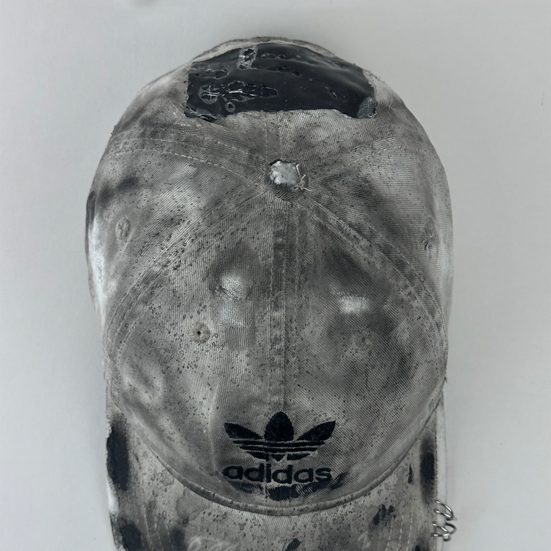 Top view of ASTROBOI* x Adidas 'H Chic' showing Adidas logo, black paint detailing, distressed finish, and stainless steel piercing detail on tan base.