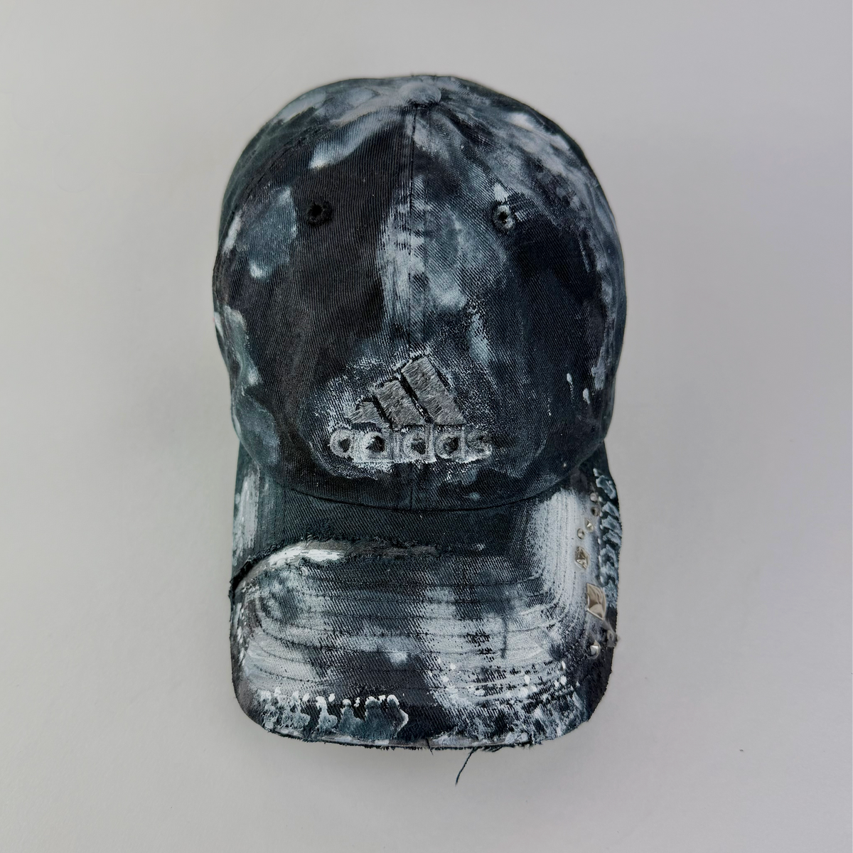 ASTROBOI* x Adidas 'Martyr' black and white faded studded rhinestone cap with Adidas logo at front, custom white faded paint treatment, and distressing throughout, front view.