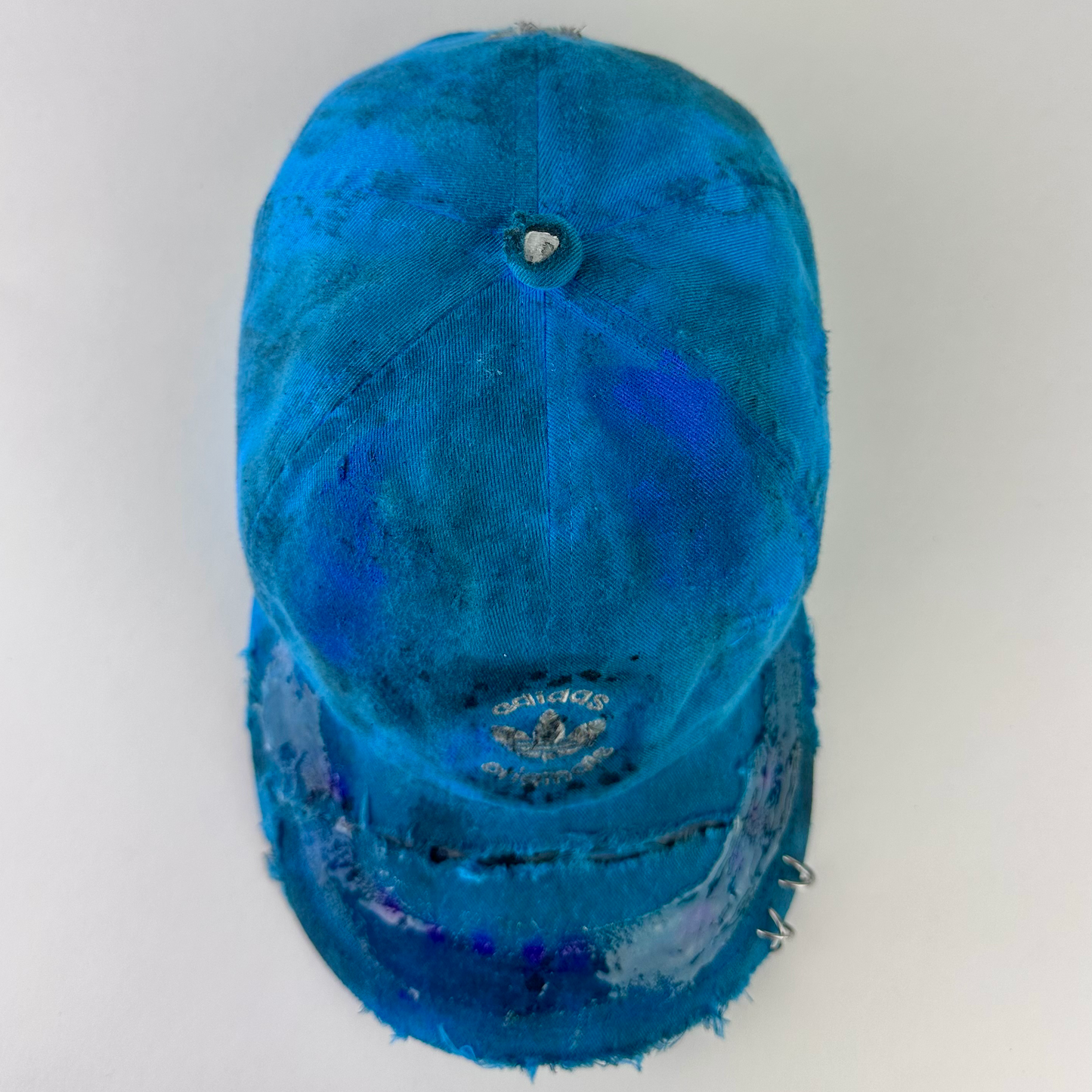 Top view of ASTROBOI* x Adidas 'Nebula' showing distressing, custom paint treatment, and resin visor detail on blue Adidas hat.
