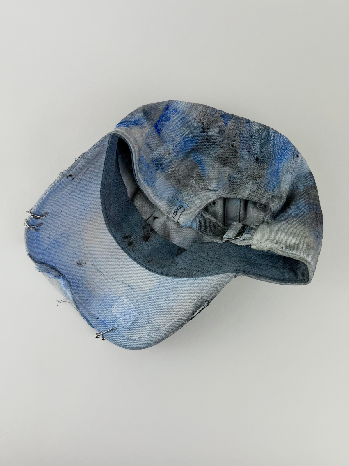 ASTROBOI* x Adidas 'Psykos' white blue and black tie-dye painted pierced grunge cap, rear view showing adjustable strap back.