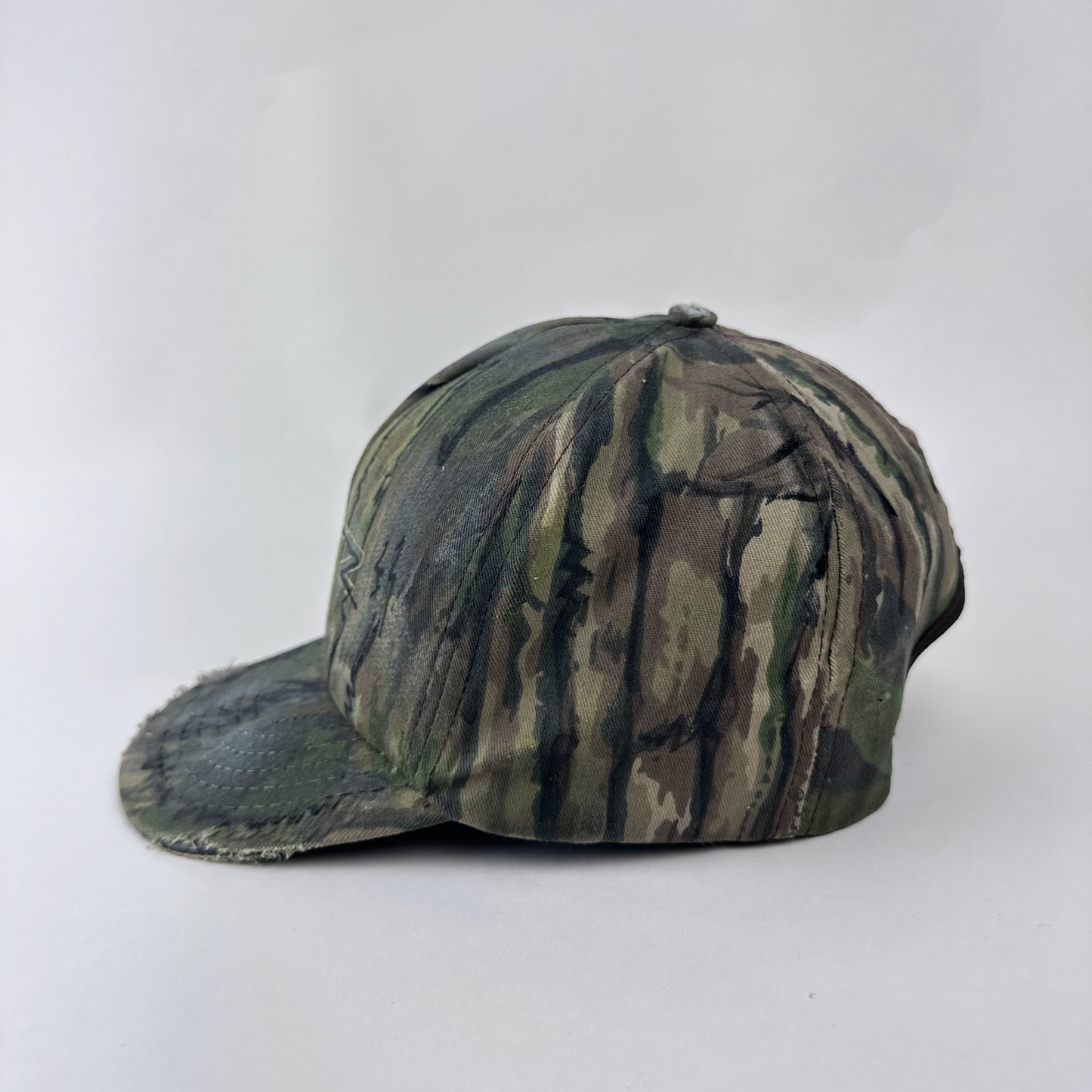 Left side detail of ASTROBOI* x Betz showing hand drawn doodle detail and custom paint treatment on brown Real Tree camo hat.