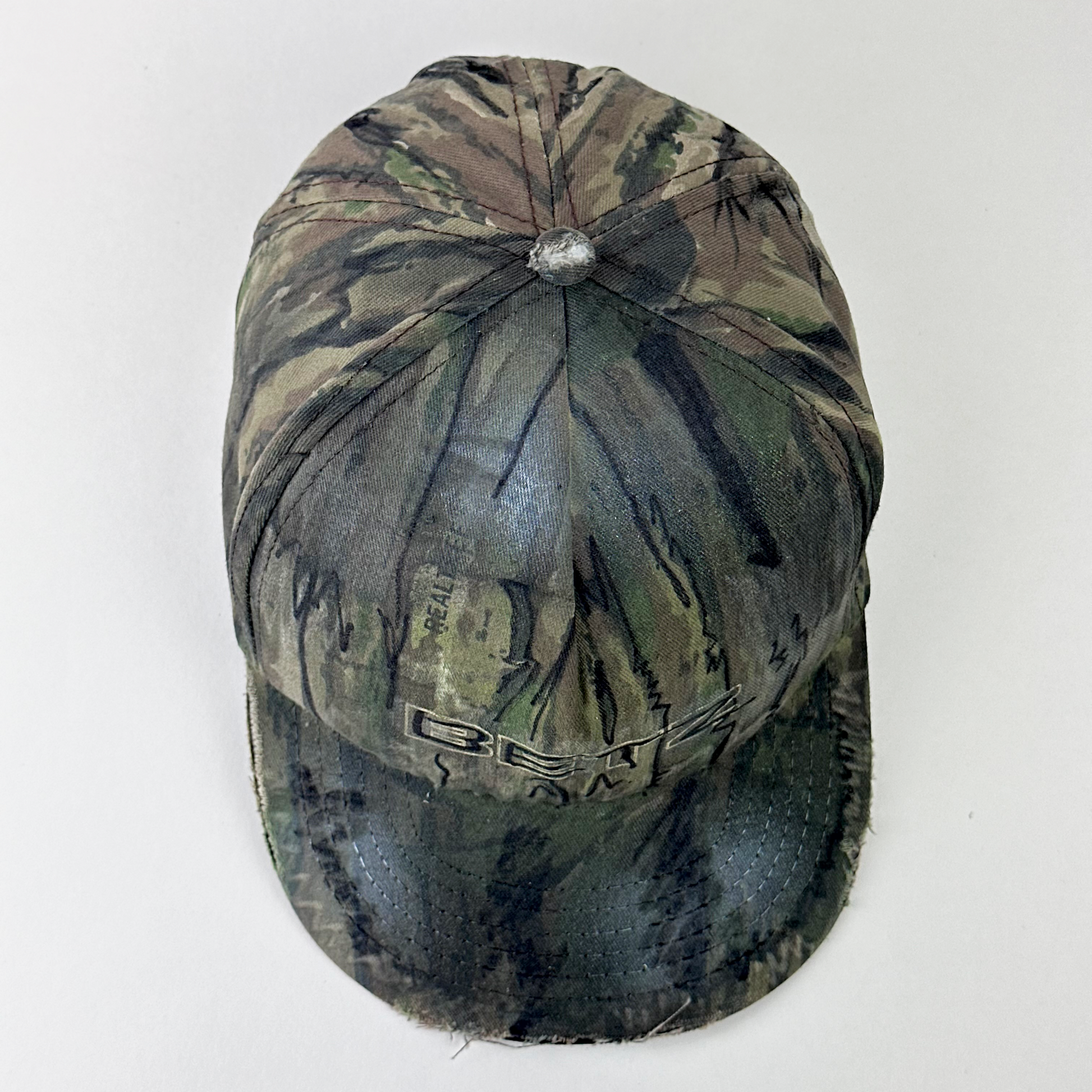 Top view of ASTROBOI* x Betz showing hand drawn doodle detail and custom paint treatment on brown RealTree camo hat.