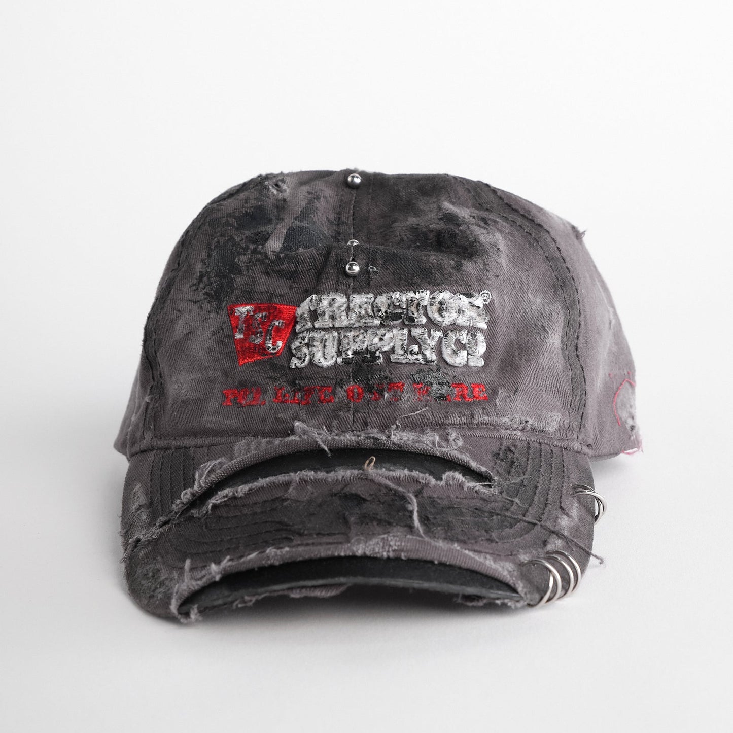 Front of ASTROBOI* Tractor Supply grey hat with black paint distressing, stainless steel piercings, adjustable strap, handmade in NYC.