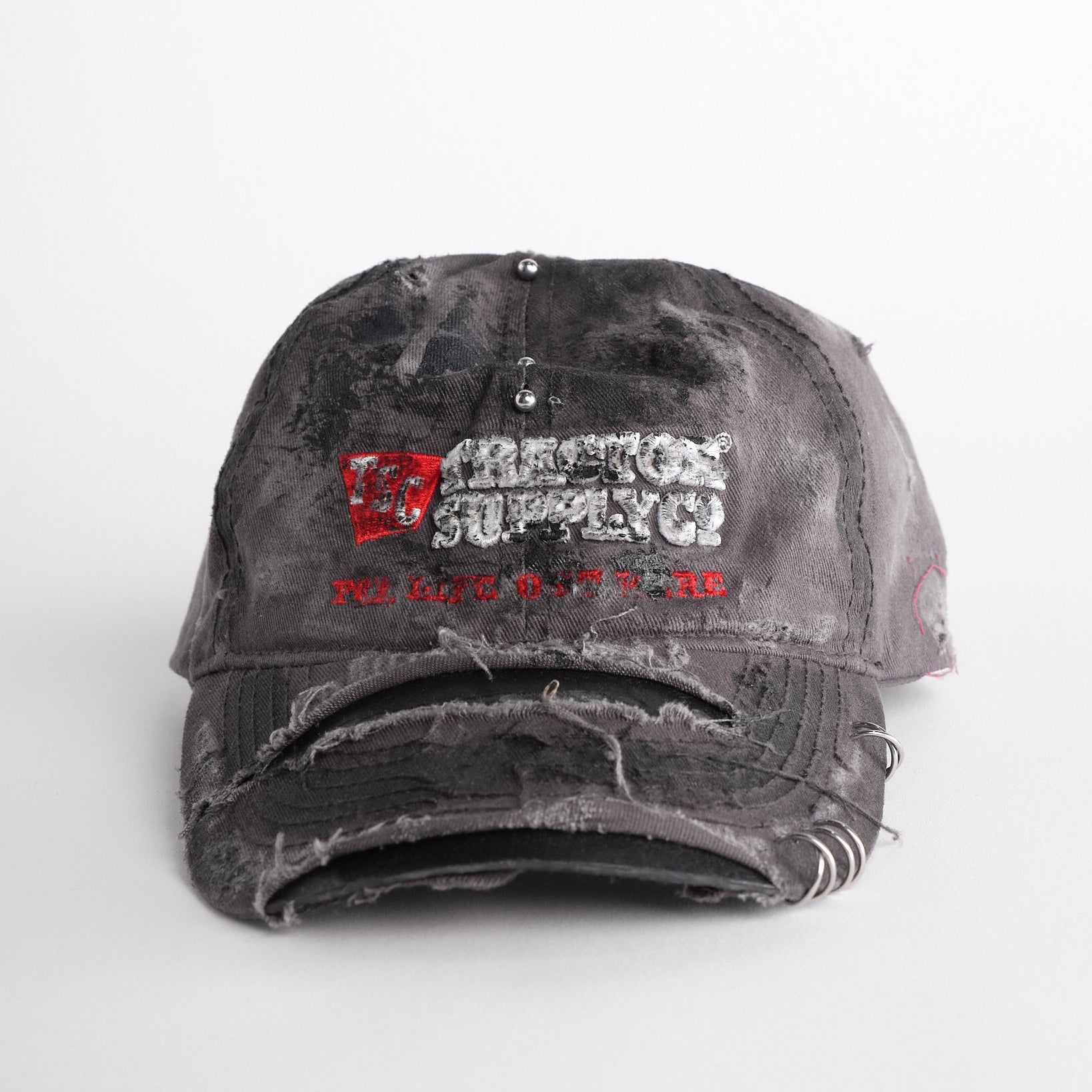Front of ASTROBOI* Tractor Supply grey hat with black paint distressing, stainless steel piercings, adjustable strap, handmade in NYC.