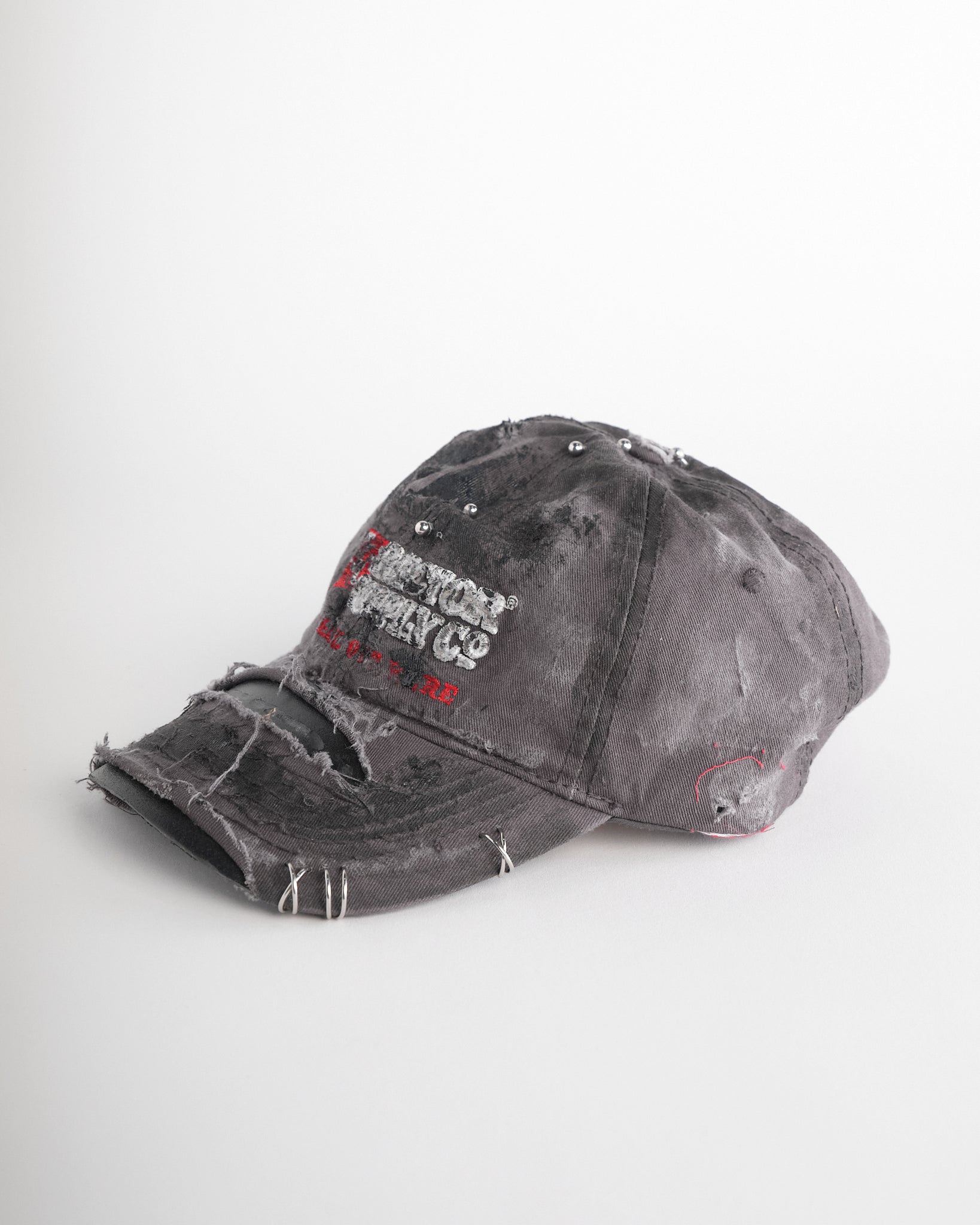 Left of ASTROBOI* Tractor Supply grey hat with black paint distressing, stainless steel piercings, adjustable strap, handmade in NYC.