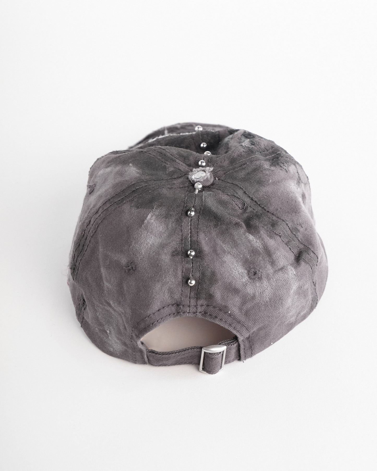 Back of ASTROBOI* Tractor Supply grey hat with black paint distressing, stainless steel piercings, adjustable strap, handmade in NYC.