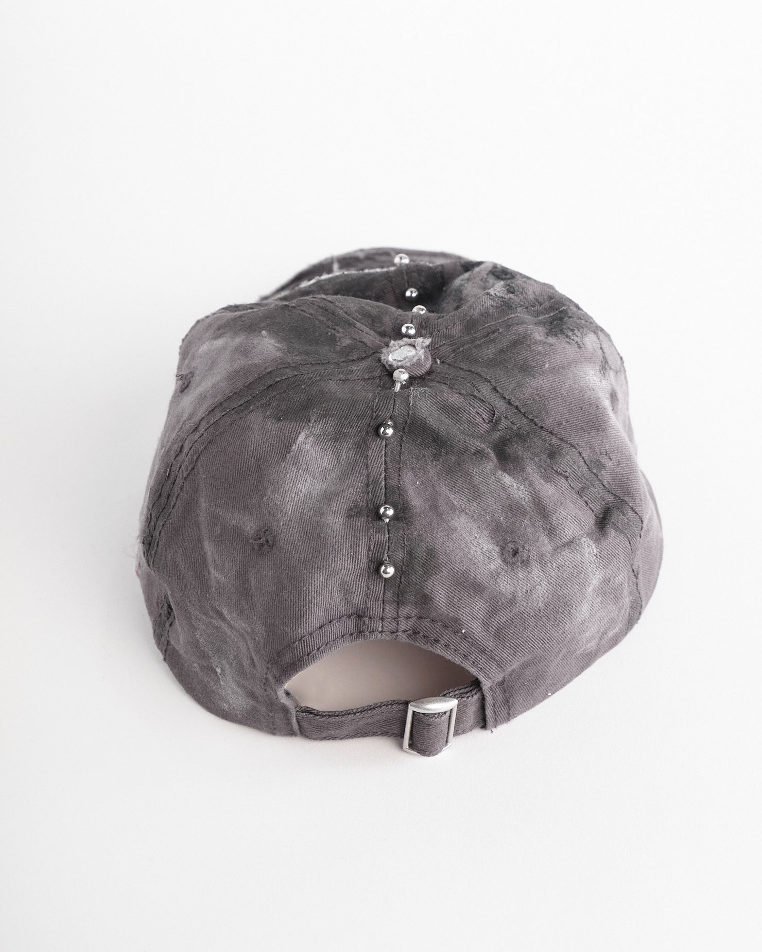 Back of ASTROBOI* Tractor Supply grey hat with black paint distressing, stainless steel piercings, adjustable strap, handmade in NYC.