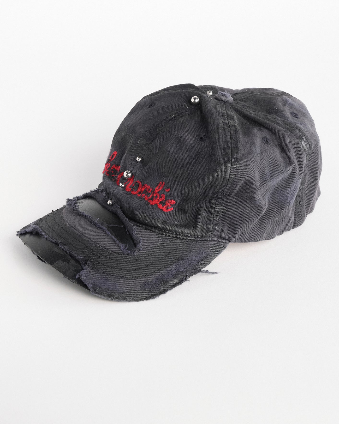 Left side of Navy ASTROBOI* x Abercrombie hat with distressed paint, stainless steel piercings, and logo embroidery on front and back, customized in NYC.