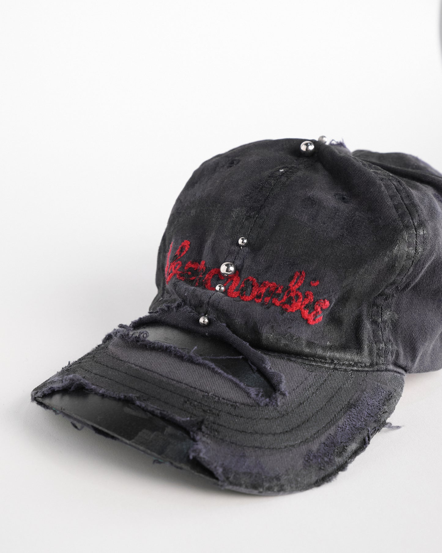 Left front detail of Navy ASTROBOI* x Abercrombie hat with distressed paint, stainless steel piercings, and logo embroidery on front and back, customized in NYC.