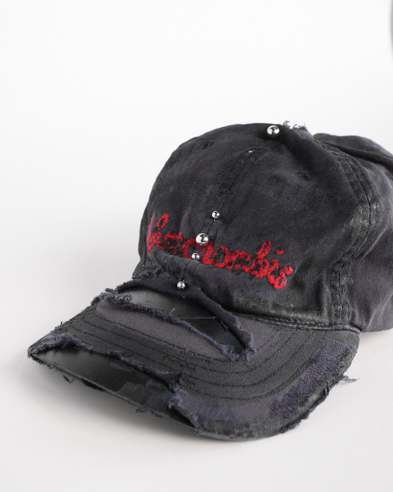 Left front detail of Navy ASTROBOI* x Abercrombie hat with distressed paint, stainless steel piercings, and logo embroidery on front and back, customized in NYC.