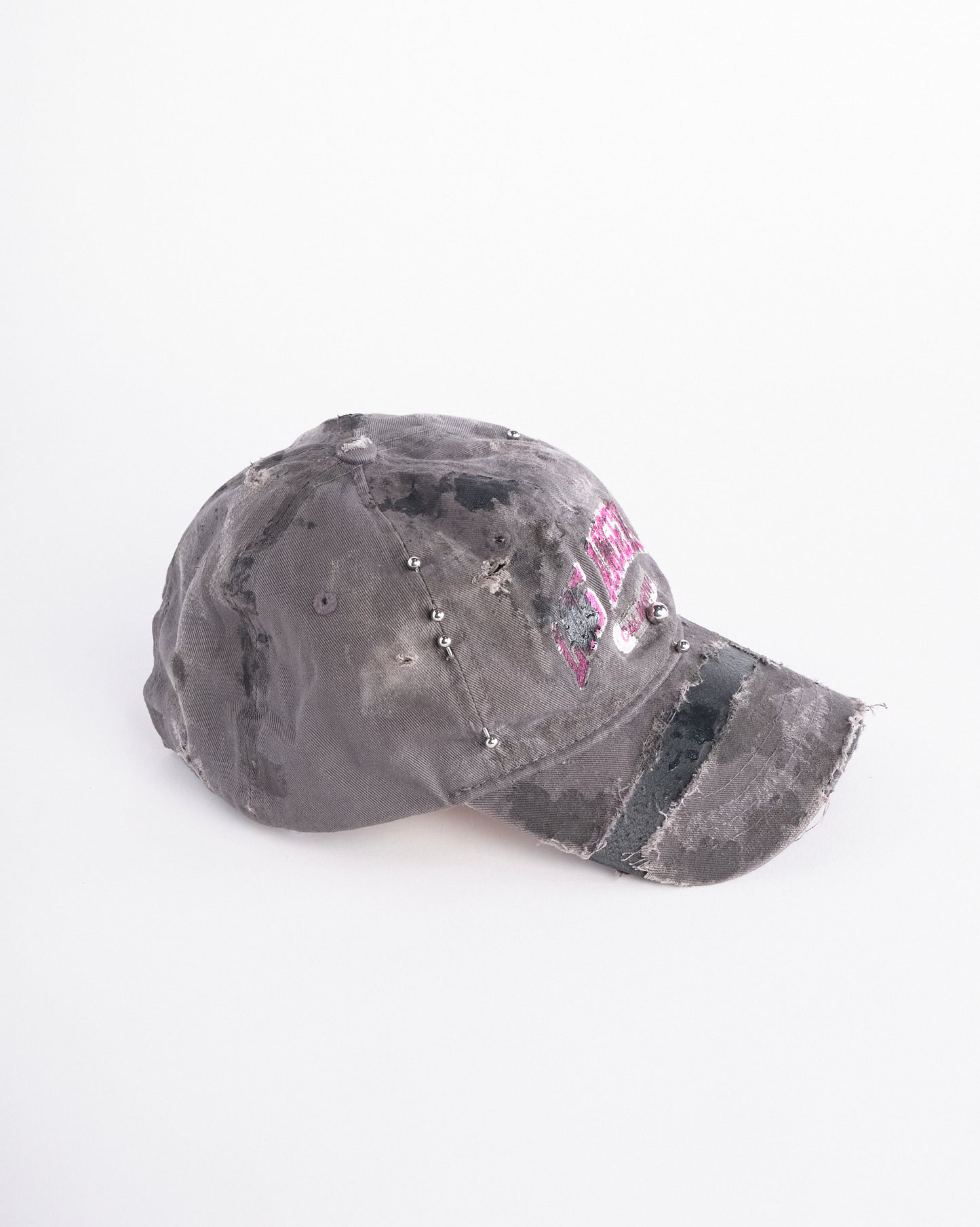 Right side of of Grey and pink distressed hat with ‘Los Angeles’ embroidery, black paint, and stainless steel piercings, customized by ASTROBOI*.