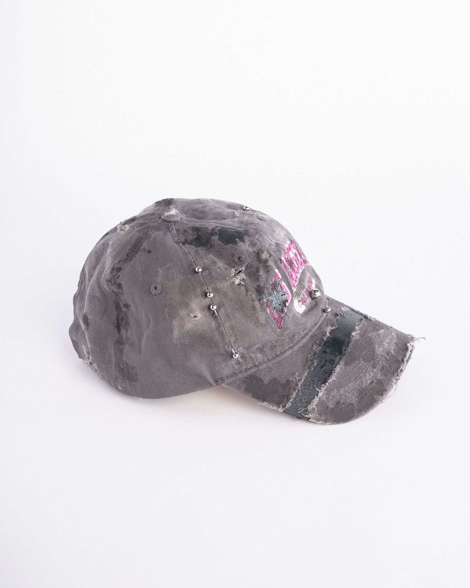 Right side of of Grey and pink distressed hat with ‘Los Angeles’ embroidery, black paint, and stainless steel piercings, customized by ASTROBOI*.