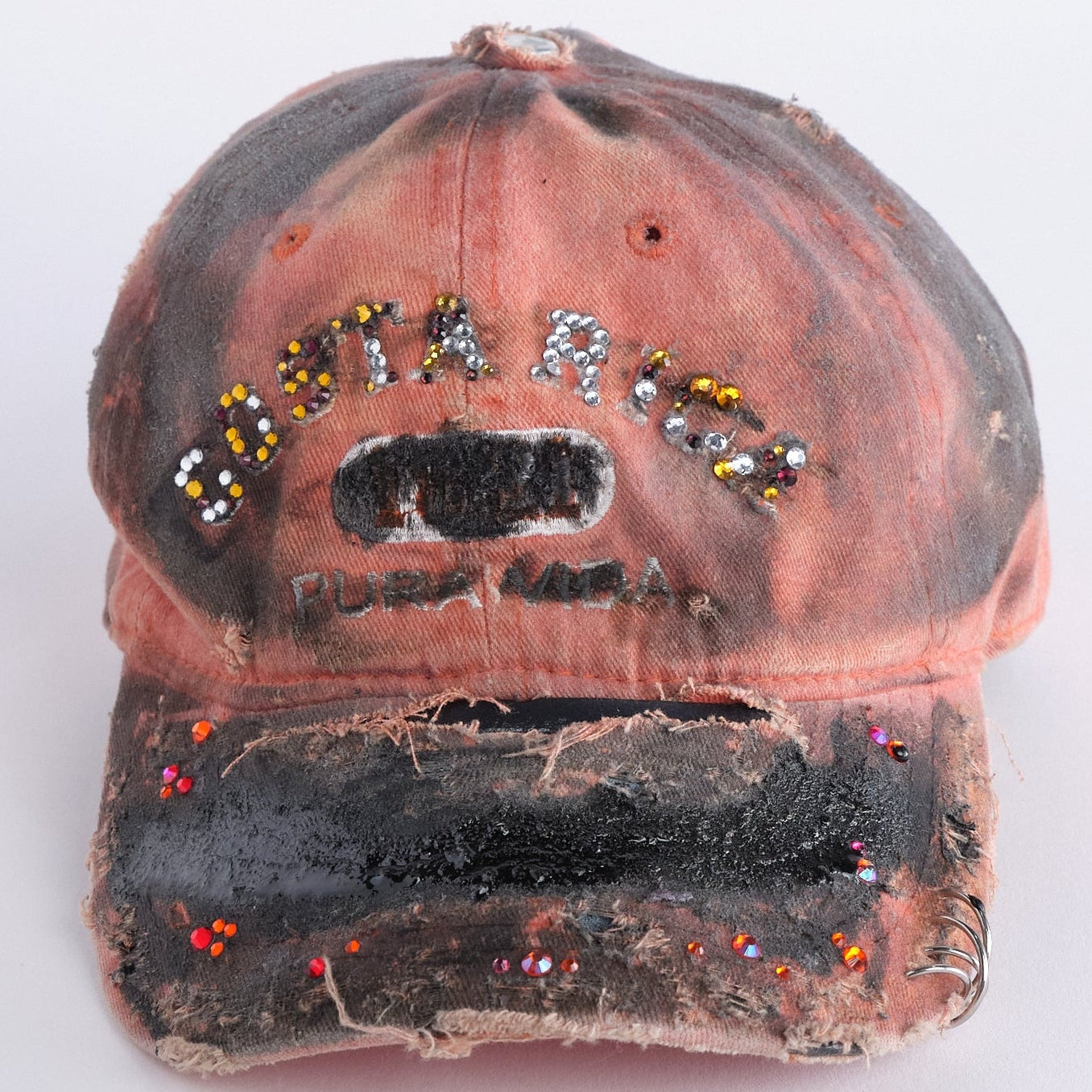 Front of ASTROBOI* Costa Rica orange distressed hat with rhinestones, black resin accents, stainless steel piercings, and adjustable strap, handmade in NYC.