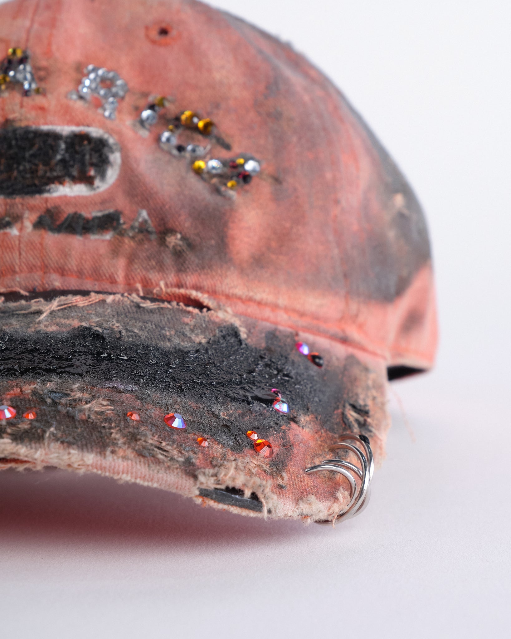 Front right detail of ASTROBOI* Costa Rica orange distressed hat with rhinestones, black resin accents, stainless steel piercings, and adjustable strap, handmade in NYC.