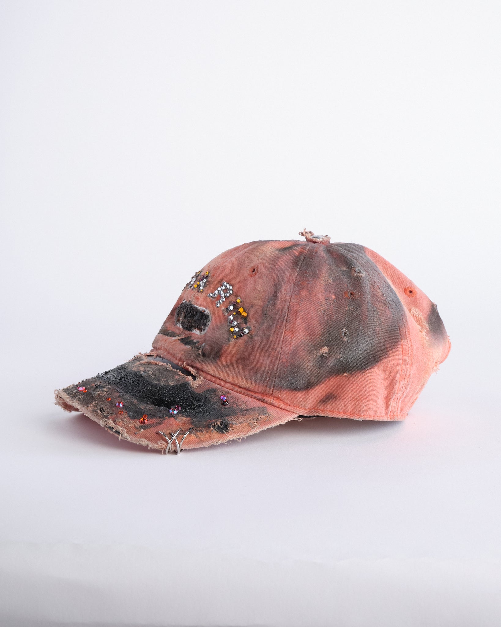 Left of ASTROBOI* Costa Rica orange distressed hat with rhinestones, black resin accents, stainless steel piercings, and adjustable strap, handmade in NYC.