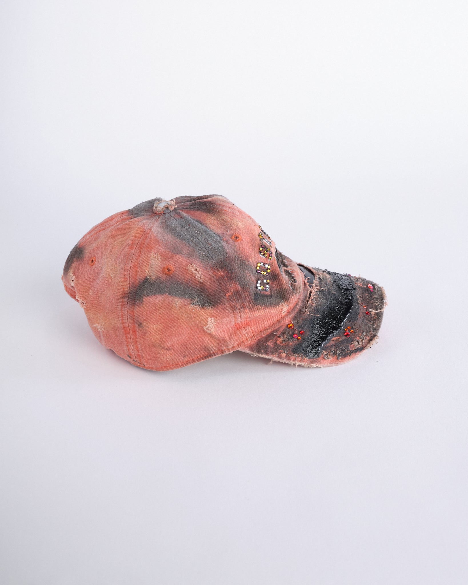 Right side of ASTROBOI* Costa Rica orange distressed hat with rhinestones, black resin accents, stainless steel piercings, and adjustable strap, handmade in NYC.