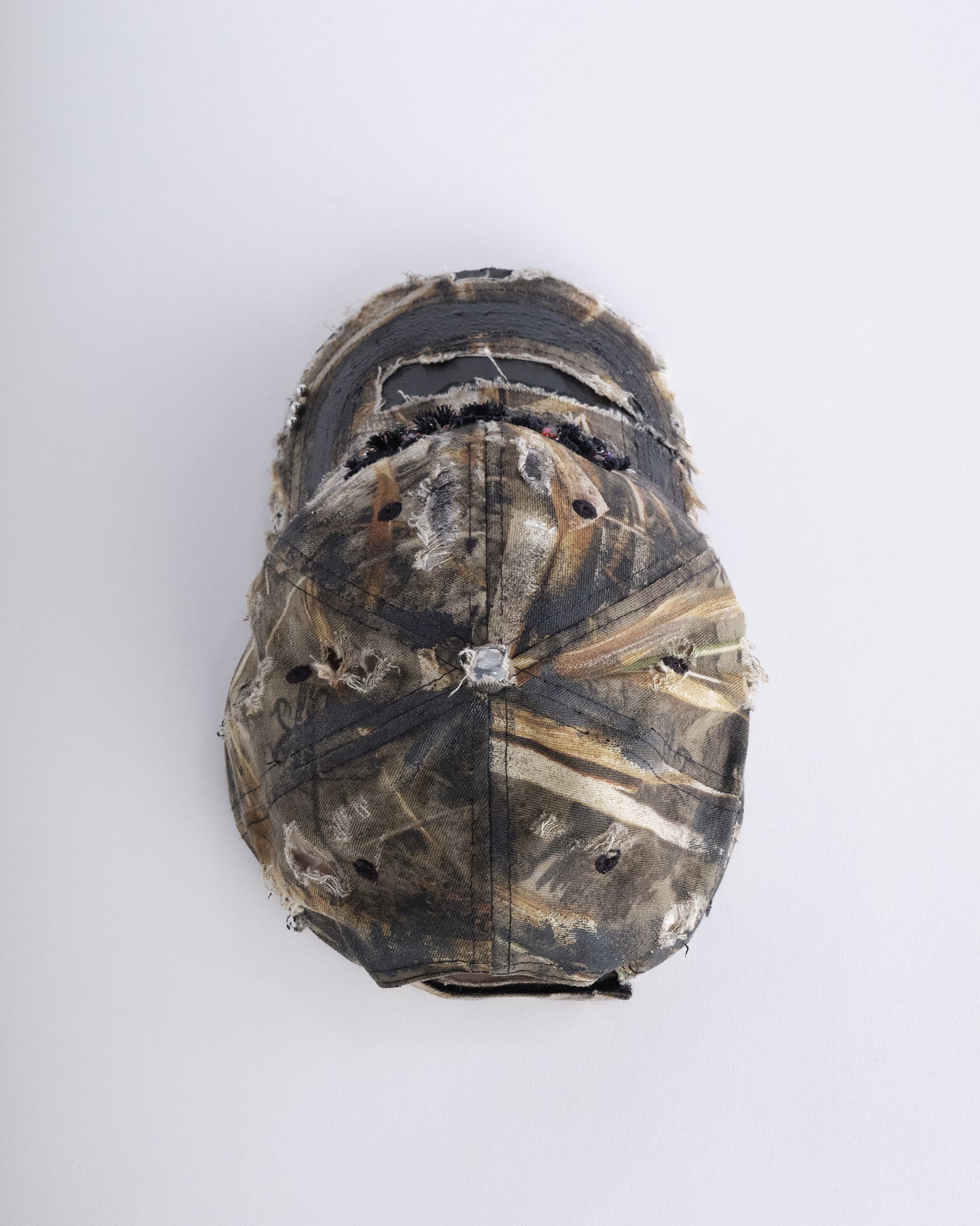 Top of ASTROBOI* DSG brown camouflage hat with rhinestone logo, black paint, clear resin accents, and stainless steel piercings, adjustable fit, handmade in NYC.