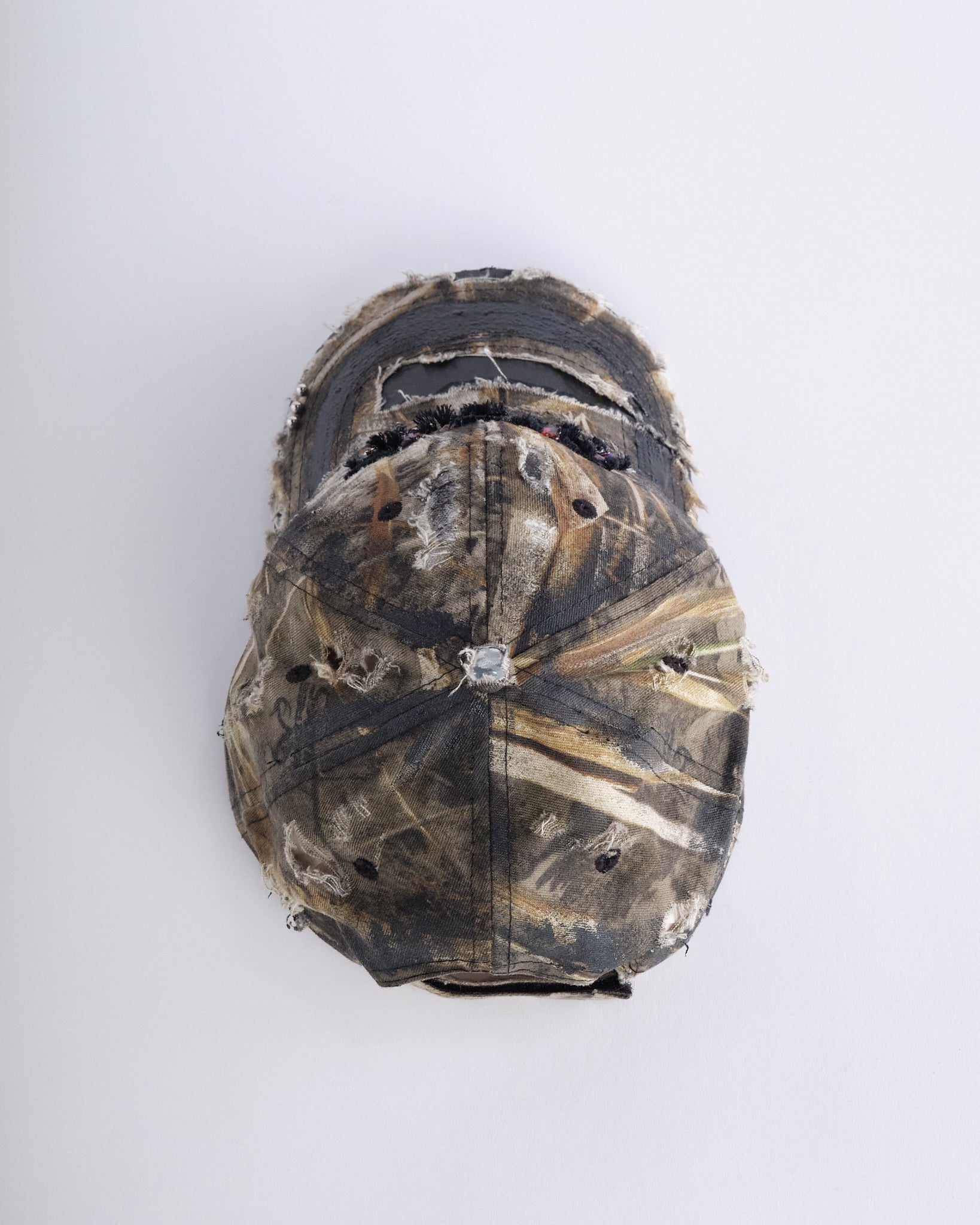 Top of ASTROBOI* DSG brown camouflage hat with rhinestone logo, black paint, clear resin accents, and stainless steel piercings, adjustable fit, handmade in NYC.