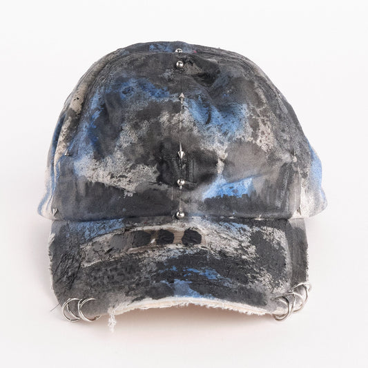 Front of Black Vuori baseball hat customized by ASTROBOI* with blue and black painted details, stainless steel piercings, and an embroidered V logo.