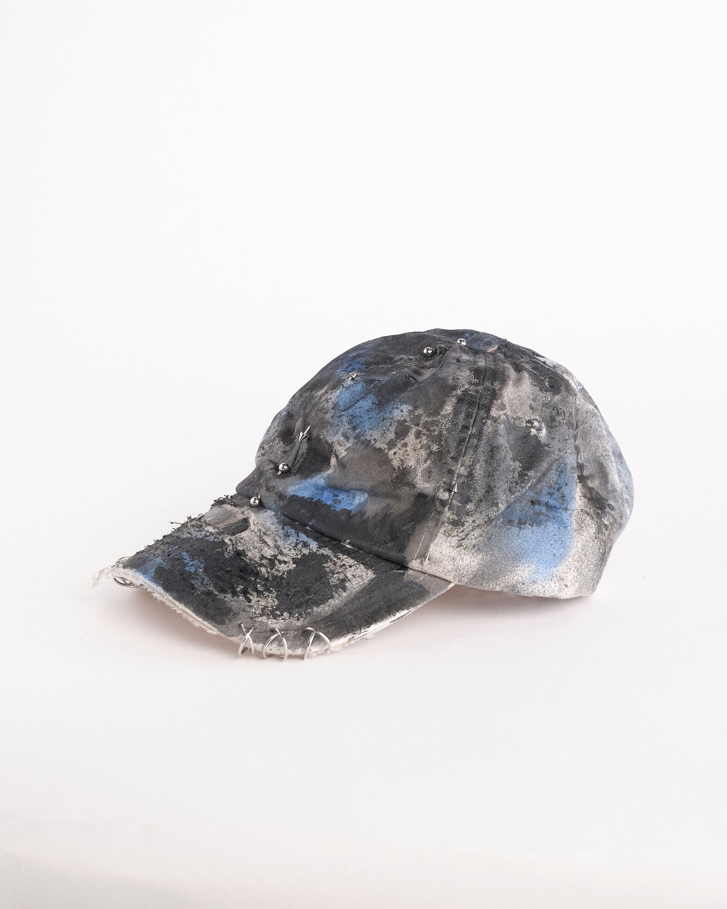 Left of of Black Vuori baseball hat customized by ASTROBOI* with blue and black painted details, stainless steel piercings, and an embroidered V logo.